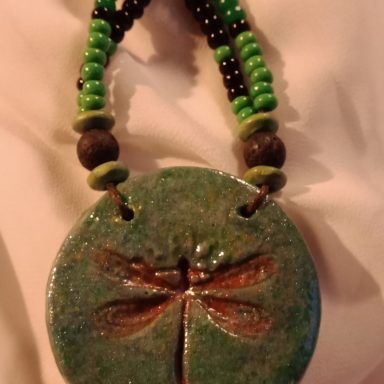 LIBELLULE Pendentif en forme de libellule, entouré de perles vertes et noires.